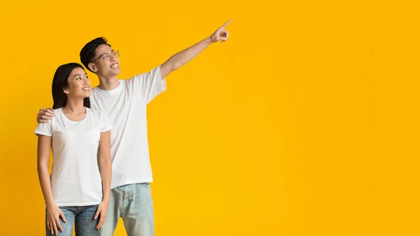 Happy asian man and woman pointing at empty space — Stock Photo, Image