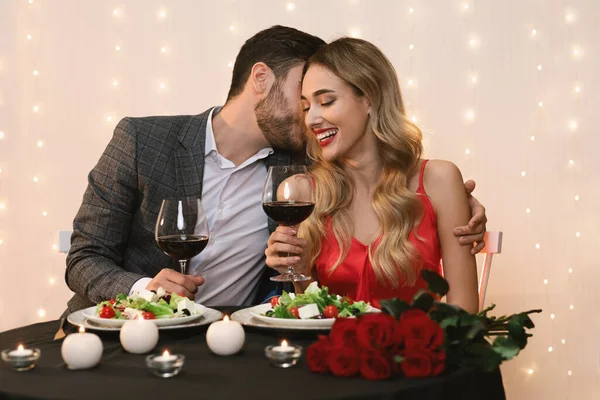 Молода пара має романтичний вечір в ресторані, обіймає і п'є вино — стокове фото