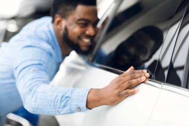 Happy Black Guy Touching His New Car In Dealership Store