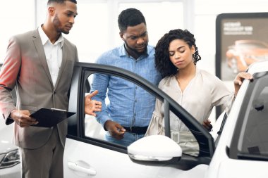 Displeased Car Buyers Choosing Automobile With Seller In Dealership Store