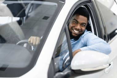 Yeni araba galerisinden gelen neşeli adam oturuyor.