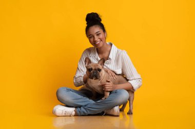 Happy black girl sitting together with her french bulldog dog puppy