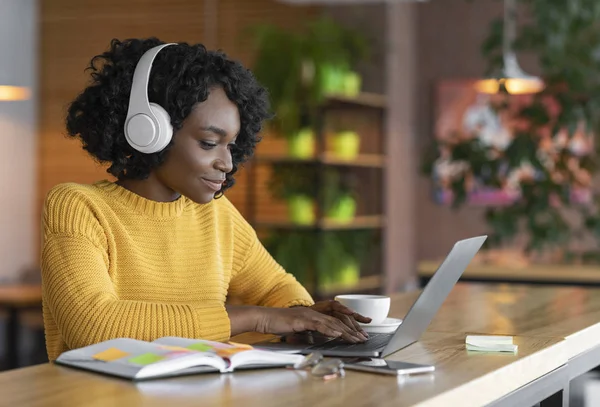 Jeune femme ayant une formation en ligne, en utilisant un ordinateur portable et un casque sans fil — Photo