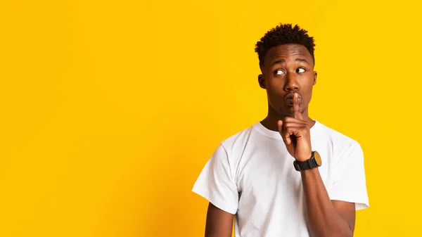 Amazed young african guy keeping finger on lips — Stockfoto