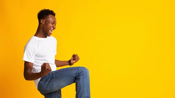 Jovem africano entusiasmado expressando sucesso no amarelo — Fotografia de Stock