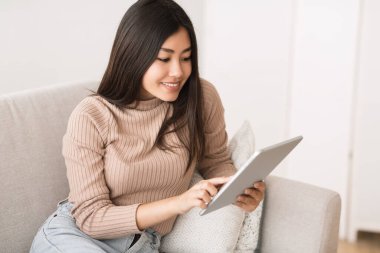 Interesting content. Asian girl reading blog on digital tablet