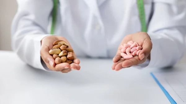 Primer plano del dietólogo sosteniendo un puñado de nueces y pastillas — Foto de Stock