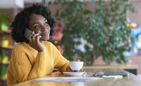 Black girl entrepreneur having conversation on phone, drinking coffee — Stockfoto