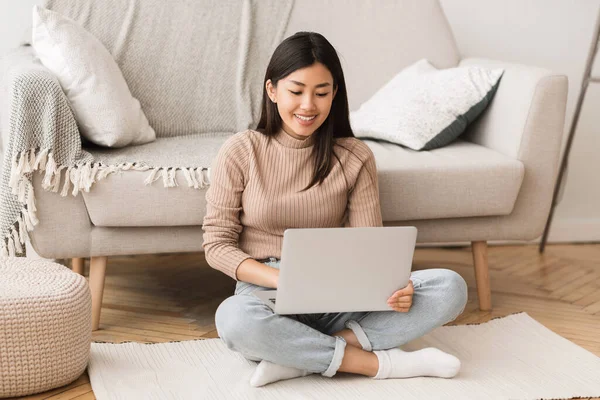 Teen asian girl networking on laptop, sitting on floor — Φωτογραφία Αρχείου