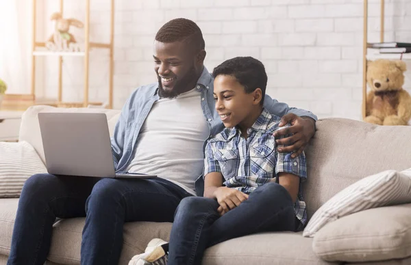Alegre negro padre y hijo viendo comedia película en portátil juntos — Foto de Stock