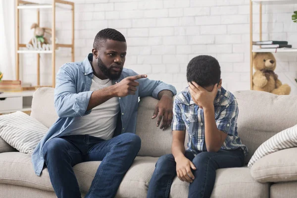 Angry black father scolding stubborn son for bad behavior at home — ストック写真