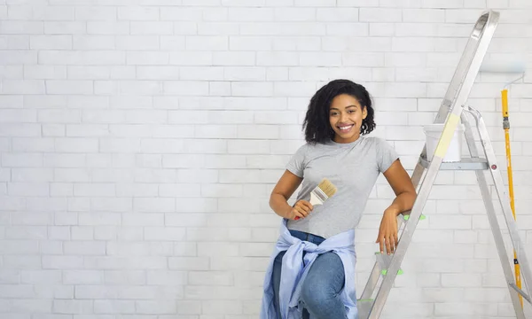 African american girl on stepladder holding a paint brush — Stock Photo, Image