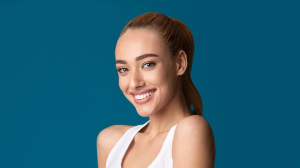 Menina sorrindo para câmera posando em fundo azul, Panorama — Fotografia de Stock