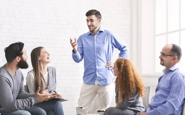 Hombre alegre contando chistes a los miembros de la comunidad en la reunión del grupo en rehabilitación —  Fotos de Stock