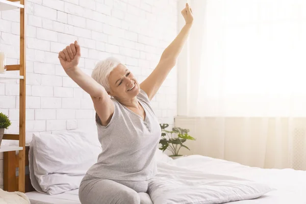 Mujer mayor bien dormida estirándose en la cama por la mañana —  Fotos de Stock