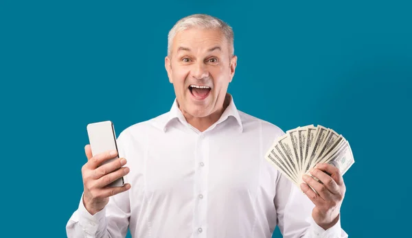 Šťastný dospělý muž drží mobilní telefon a peníze — Stock fotografie