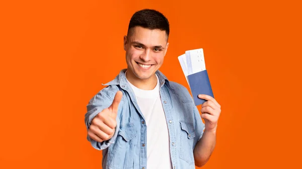 Felice ragazzo in possesso di passaporto con biglietto e mostrando pollici in su — Foto Stock