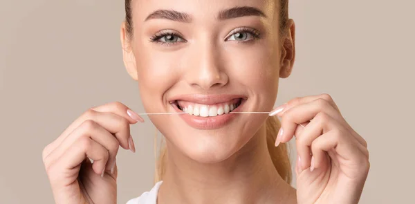 Femme souriante utilisant Floss nettoyage des dents posant sur fond beige — Photo