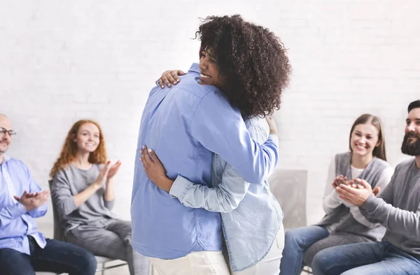 Pareja abrazándose delante del grupo después de una exitosa sesión de terapia matrimonial — Foto de Stock