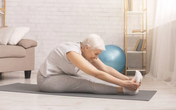 Fit senior woman stretching at home, free space — Stock Photo, Image