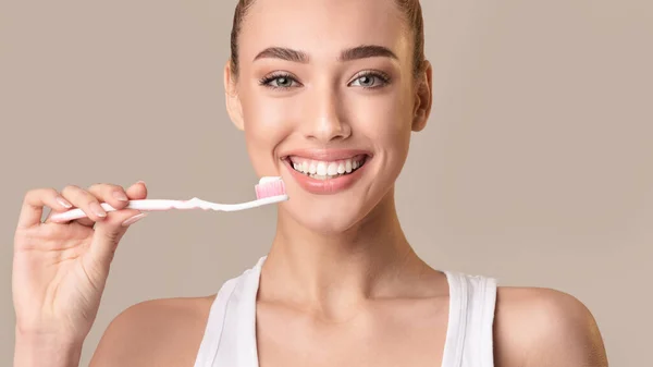 Cepillo de dientes con pasta de dientes limpiando dientes, fondo beige, Panorama — Foto de Stock