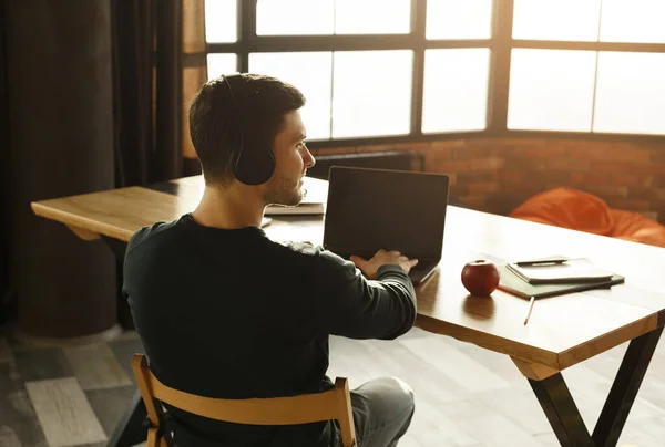 Freelancer em fones de ouvido trabalhando no laptop no espaço de trabalho cooperativo, Back-View — Fotografia de Stock