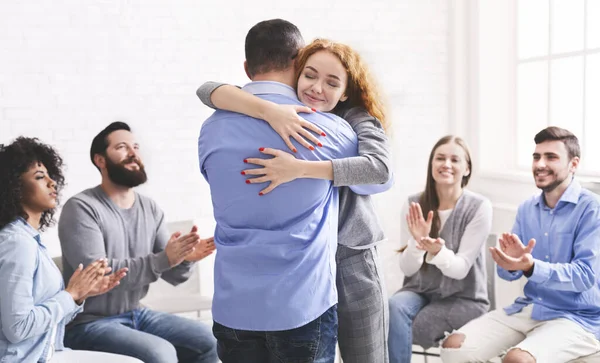 Glückliche Menschen, die einander nach der Therapiesitzung umarmen und applaudieren — Stockfoto