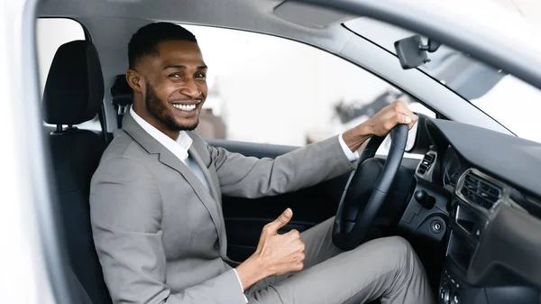 Üzletember vásárol autó Gesturing hüvelykujj-up a sofőrök ülés a bemutatóteremben — Stock Fotó