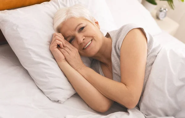Calmo mulher idosa deitada na cama e sorrindo — Fotografia de Stock