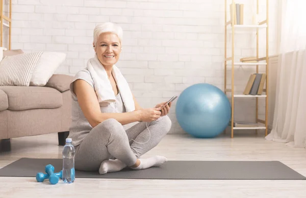 Mujer mayor activa descansando con el teléfono celular después del entrenamiento — Foto de Stock