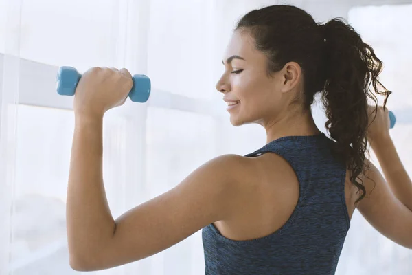 Deportiva chica hispana en entrenamiento con mancuernas en gimnasio — Foto de Stock