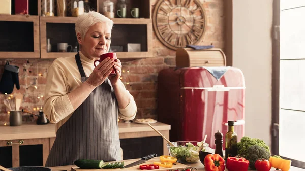 Entspannte ältere Frau genießt heißen Kaffee in Küche — Stockfoto