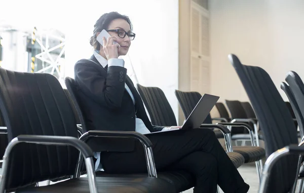 Femme concentrée assise dans la salle de conférence et parlant au téléphone — Photo