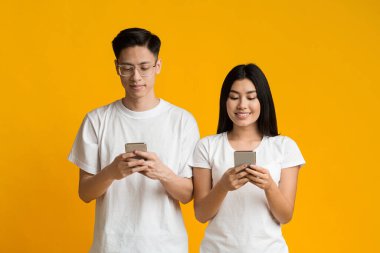 Neşeli Asyalı milenyum çifti cep telefonlarını karıştırıyor