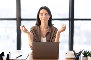 Ofiste meditasyon yapan bir kız işte stresle boğuşuyor.