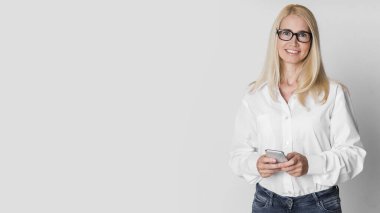 Gülümseyen olgun yönetici kameraya bakarak cep telefonu kullanıyor.