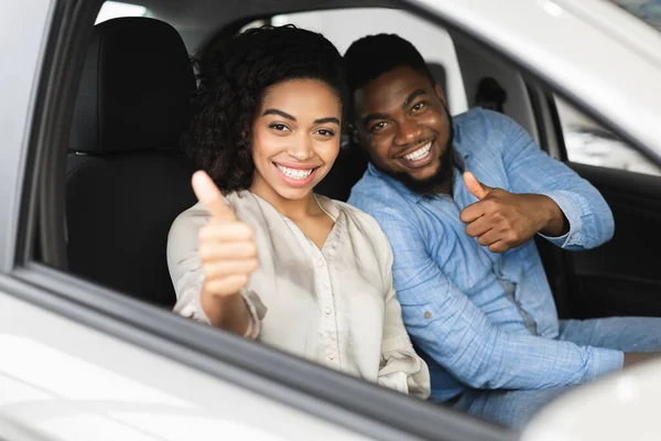 Glückliches Paar gestikuliert Daumen hoch im Autohaus — Stockfoto