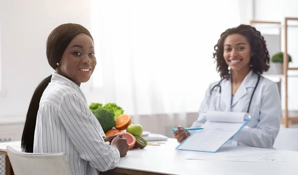 Schwarze junge Frau lässt sich im modernen Büro vom Diätologen beraten — Stockfoto