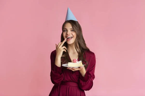 Vrolijk meisje likken crème van verjaardag taart in haar handen — Stockfoto