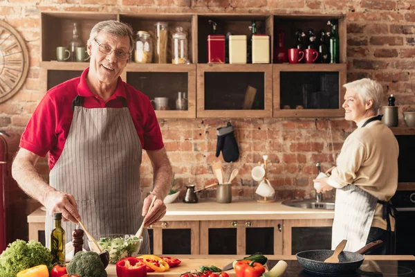 Yaşlı çift sağlıklı yiyecekler hazırlıyor, mutfakta birlikte vakit geçiriyorlar. — Stok fotoğraf
