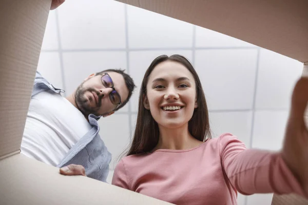 Pareja joven positiva mirando en una caja de cartón — Foto de Stock