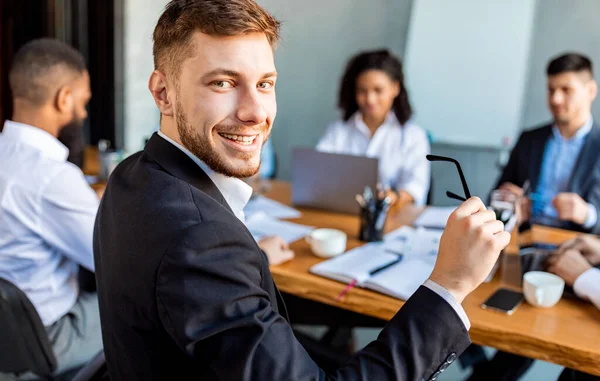 Homme d'affaires à la réunion avec des collègues souriant assis dans le bureau moderne — Photo