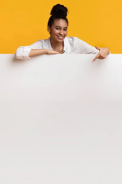 Smilimg Afro ragazza appoggiata e puntando a bordo pubblicità bianca — Foto Stock