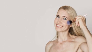 Güzel, beyaz, orta yaşlı kadın fırçasını kullanıyor.