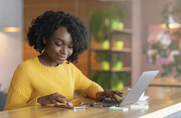 Empresária afro positiva trabalhando on-line e usando telefone celular — Fotografia de Stock