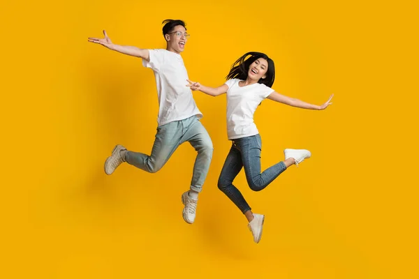 Emocjonalna azjatycka para skacząca po żółtym tle — Zdjęcie stockowe