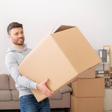 Man transferring heavy box while moving in new apartment