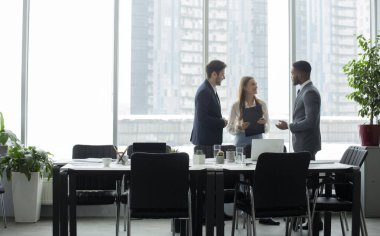 Coffee break. Businesspeople talking in front of office window