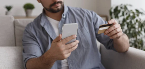 Male hands holding credit card and using modern smart phone — Φωτογραφία Αρχείου