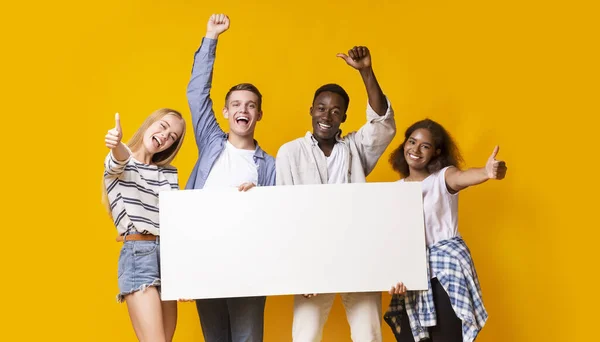 Portrait of excited group of teenagers holding empty advertising board — Stok fotoğraf